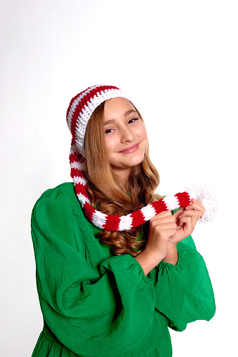 vertical Christmas portrait of cheerful girl in new year green wear holds hands near face on white studio background