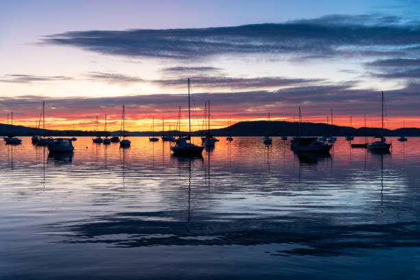 istock Sunrise over the water with boats, reflections and high cloud 1667400468