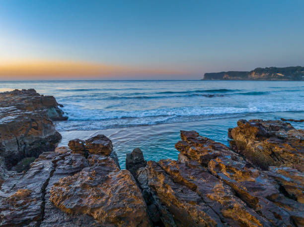istock Sunrise over the ocean and rock platform with clear skies 1667402209