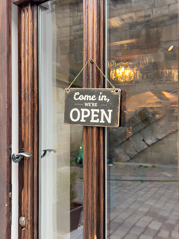 open sign, vintage come in we are open entrance sign hanged on a window door of a small shop or store. entrance of a cafe or shop with sign. small business concept background