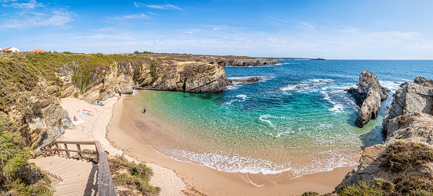 View of Praia dos Buizinhos sand beach with ocean waves and sharp rock and cllifs at wild Vicentine coast in Porto Covo, Alentejo, Portugal.
