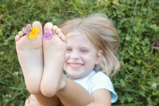 Child feet on green grass, barefoot little girl on meadow, countryside lifestyle, concept of grounding and connecting with nature