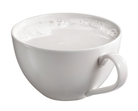 a cup of milk with cream and bubbles isolated on white background with clipping path