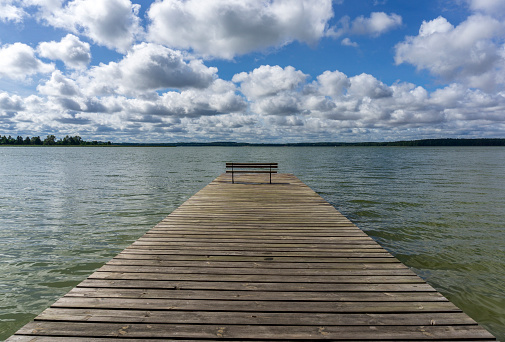 Wooden pier against the background of the lake and clouds.