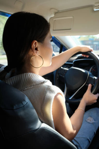 istock Young asian woman drives a car. Back view 1667472276