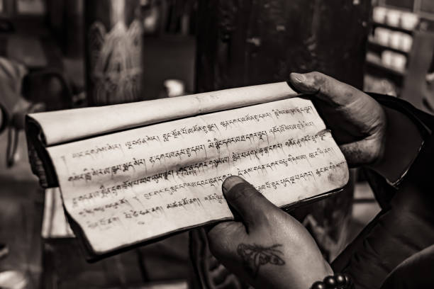 Black and white image with distinctive hands holding a Tibetan text about recession in a monastery in Tibet