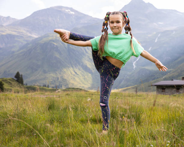 istock A girl with mischievous pigtails resting in the mountains, doing stretching in a mountain meadow in an Austrian valley 1667500355