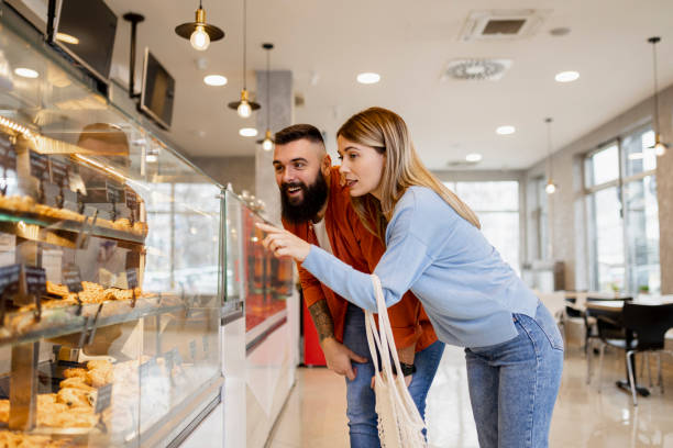 istock Beautiful young couple is choosing pastries and smiling while doing shopping at the bakery 1667517556