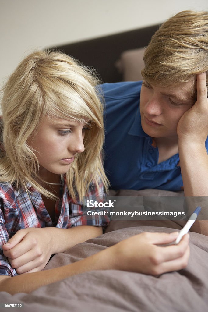 Teenagers Lying On Bed Looking At Pregnancy Testing Kit Two Teenagers Lying On Bed Looking At Pregnancy Testing Kit Adolescence Stock Photo