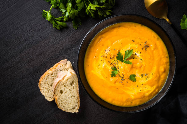 istock Pumpkin soup puree with cream at black stone table. 1667559200
