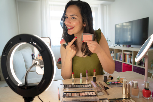 Beauty blogger presenting makeup cosmetics in front of camera