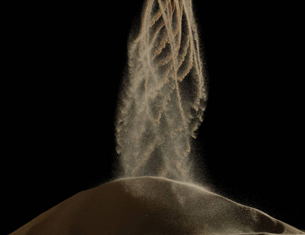 istock Sand fall down as spiral wave tornado storm in air. Sand dune hill over wind storm and blast dust splash over mountain. Sunshine rain fall on sand hill wind blow. Black background isolated 1667589605