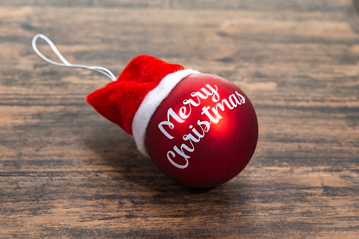 Red Christmas ball with words Merry Christmas on wooden background