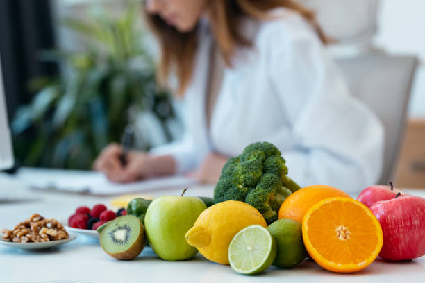 Beautiful smart nutritionist woman working with computer while taking notes in the nutritionist consultation