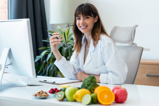 istock Beautiful smart nutritionist woman working with computer while looking at camera in the nutritionist consultation 1667608785