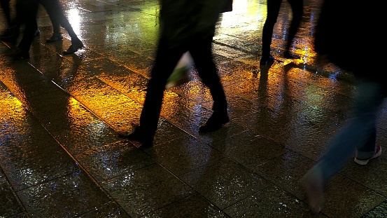 Businessmen and Commuters Walking Wet Pavement in Rainy Evening