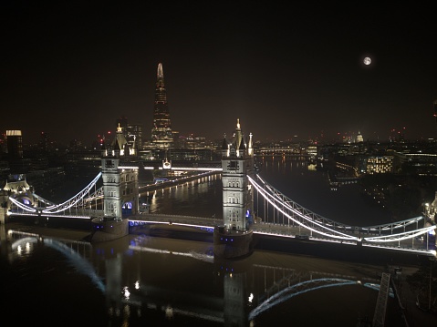 An aerial view of London's Tower Bridge at night with St Paul's Cathedral and the Shard in the background