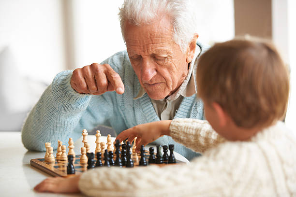 Teaching his grandson about chess A grandfather teaching his grandson how to play chess senior chess stock pictures, royalty-free photos & images