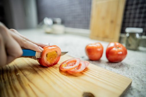 Close-up of a woman slicing tomatoes on cutting board