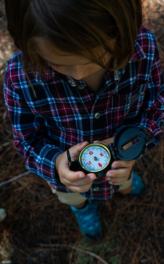 Child in nature looking at a compass