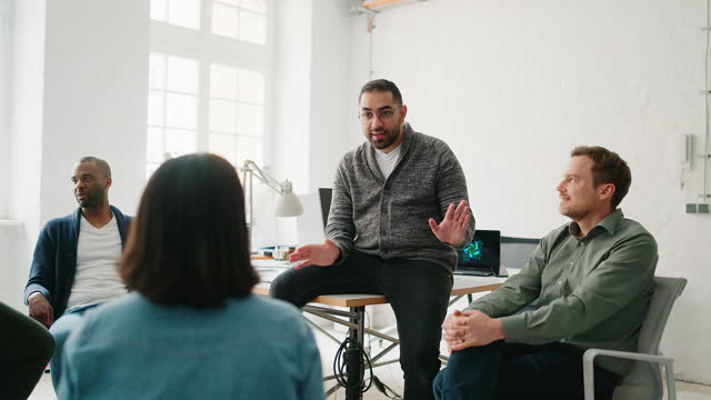 Young man discussing work with team in meeting at coworking office