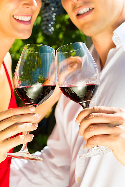 Woman and man standing at vineyard drinking wine