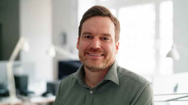 Portrait of happy young businessman standing in open plan office