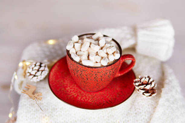 istock A stack of knitted sweaters, a red cup of cocoa with marshmallows, a garland with Christmas decorations on a wooden background. 1667647905