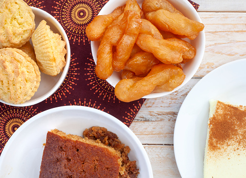 Traditional South African sweet food on rustic wood with traditional printed cloth. Milk tart, koek sisters and malva pudding