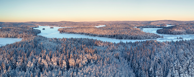 Aerial view over a forest and lake (lake; Norra Barken) landscape in winter in the Dalarna region of Sweden.