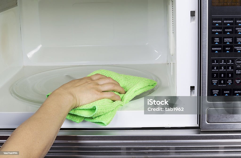 Cleaning inside of Microwave Oven Hand with microfiber cleaning rag wiping inside of microwave oven Cleaning Stock Photo