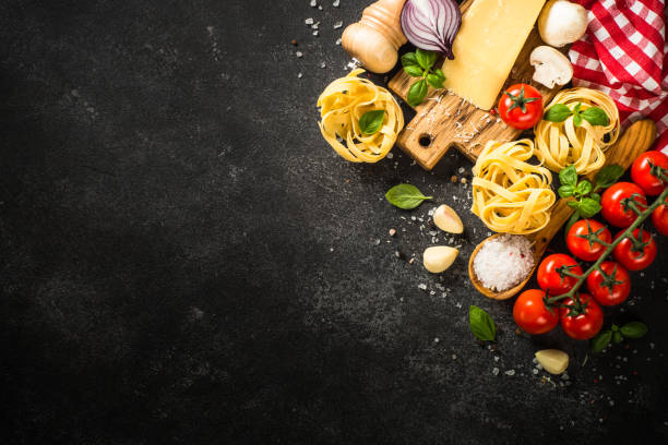 istock Pasta ingredients on black background.  Top view with copy space. 1667683344