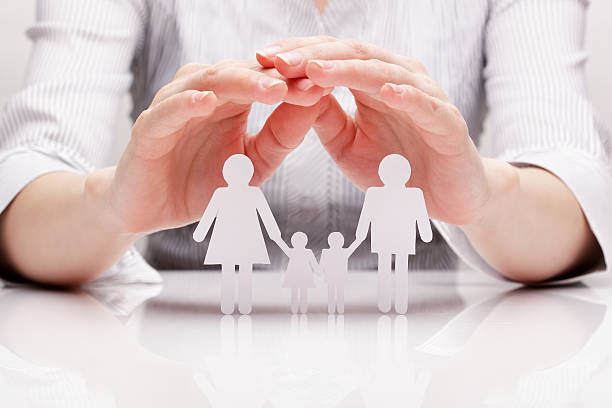 Closeup of hands cupping over white paper cutout of a family Hands hug the family legal defense photos stock pictures, royalty-free photos & images