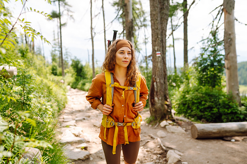 Woman travels along hiking trails among the mountains with a yellow backpack and hiking boots. The concept of travel, vacation, adventure, hiking.