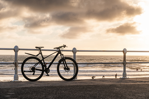 Silhouette of a bicycle in the setting sun on the beach.