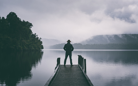 Sporting an Indiana Jones-style hat, a man in his fifties takes in the wonders of Lake Mapourika, on the West Coast of New Zealand's South Island.