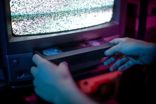 Close up of hands insert vhs into old cathode screen\nretrowave and aesthetic vibes