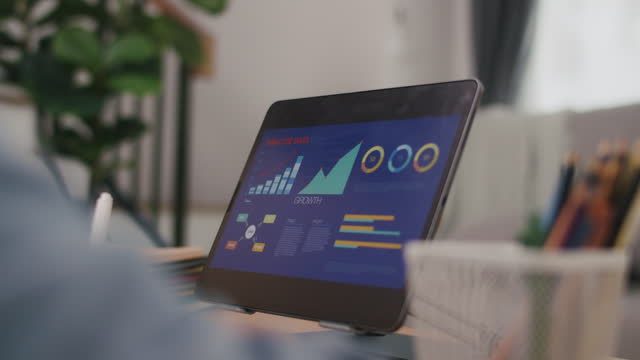Asian male using a tablet for the business stock market, trading, infographic, charts, and data numbers insight analysis for the business meeting.