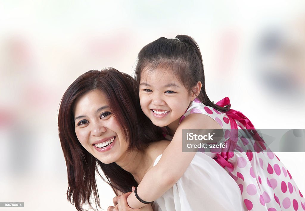 Asian family piggyback ride at home. Asian family at home. Mother and child piggyback ride at indoor room. Adult Stock Photo