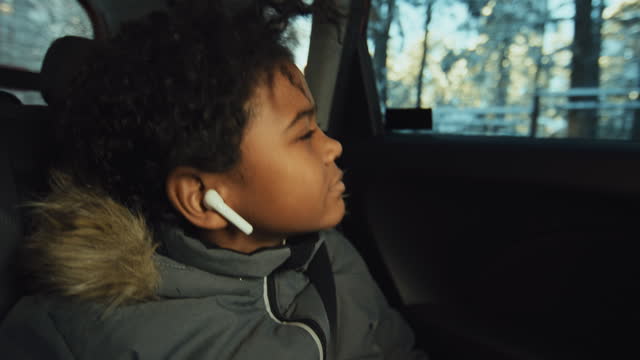 Teenage Boy Listening to Music in Earphones in Car