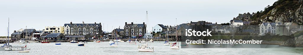 Barmouth Maritime village panorama Panoramic photograph of the Barmouth marina with houses and cafes built on a peninsula and boats floating by. Bay of Water Stock Photo