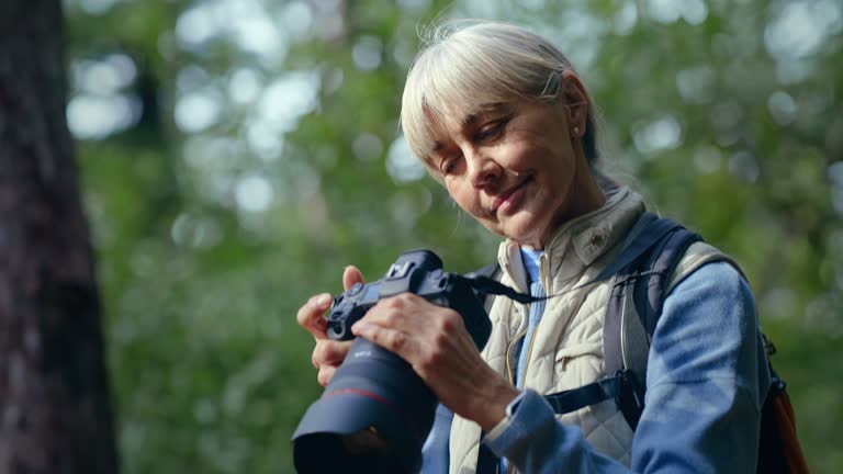 Woman, hiking and professional photography in forest, jungle or woods for environment, research or tourism. Mature person or photographer with camera lens, shooting in nature for eco friendly travel