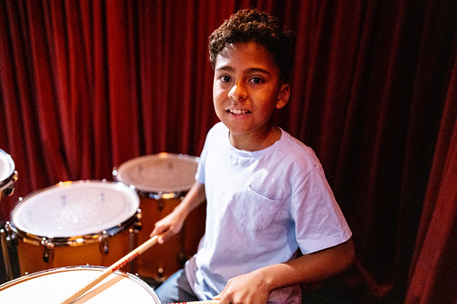 Portrait of a boy playing drums in a music school