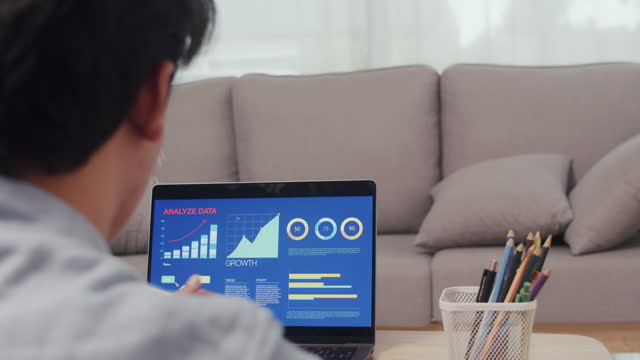 Asian man using a laptop for the business stock market, trading, infographic, charts, and data numbers insight analysis for the business meeting.