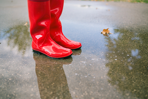 Rubber boots are jumping into a big puddle with splash.