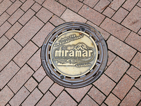 The manhole cover is made of metal with a pattern unique to the city. It is also an interesting spot for tourists to stop by and take photos as a souvenir.weinheim, Germany, 2023-04-02.