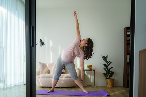 Tranquil aura envelops as an Asian woman finds solace through yoga and meditation at home, a serene journey within four walls.