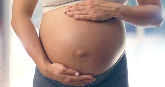 Pregnant woman, stomach and hands closeup with mother love for fitness and exercise. Zen, peace and mindfulness of new mom holding belly for support and care with training and balance for health