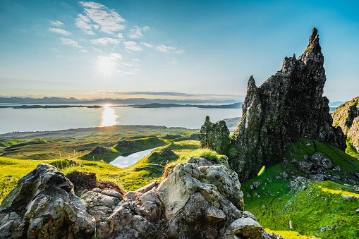 Breathtaking view of popular Scottish travel destination; The Old Man of Storr on the Isle of Skye. Dramatic clouds cover the morning sky with vibrant colours from the sunrise in the foreground.