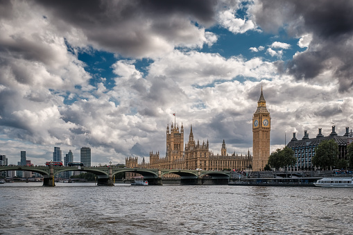 Big Ben and the Houses of Parliament with buses crossing the Westminster bridge passing over the River Thames in london
